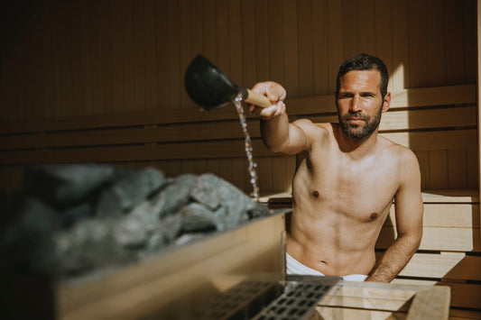 Uomo che versa acqua sulle pietre calde della sauna.