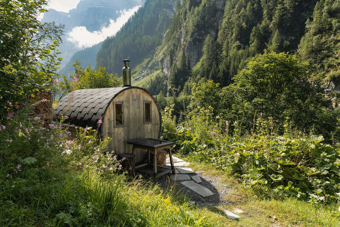 Piccola sauna in legno in un bosco con tavolo all'aperto.