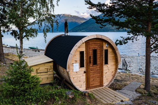 Sauna a botte con tetto nero in riva al lago.