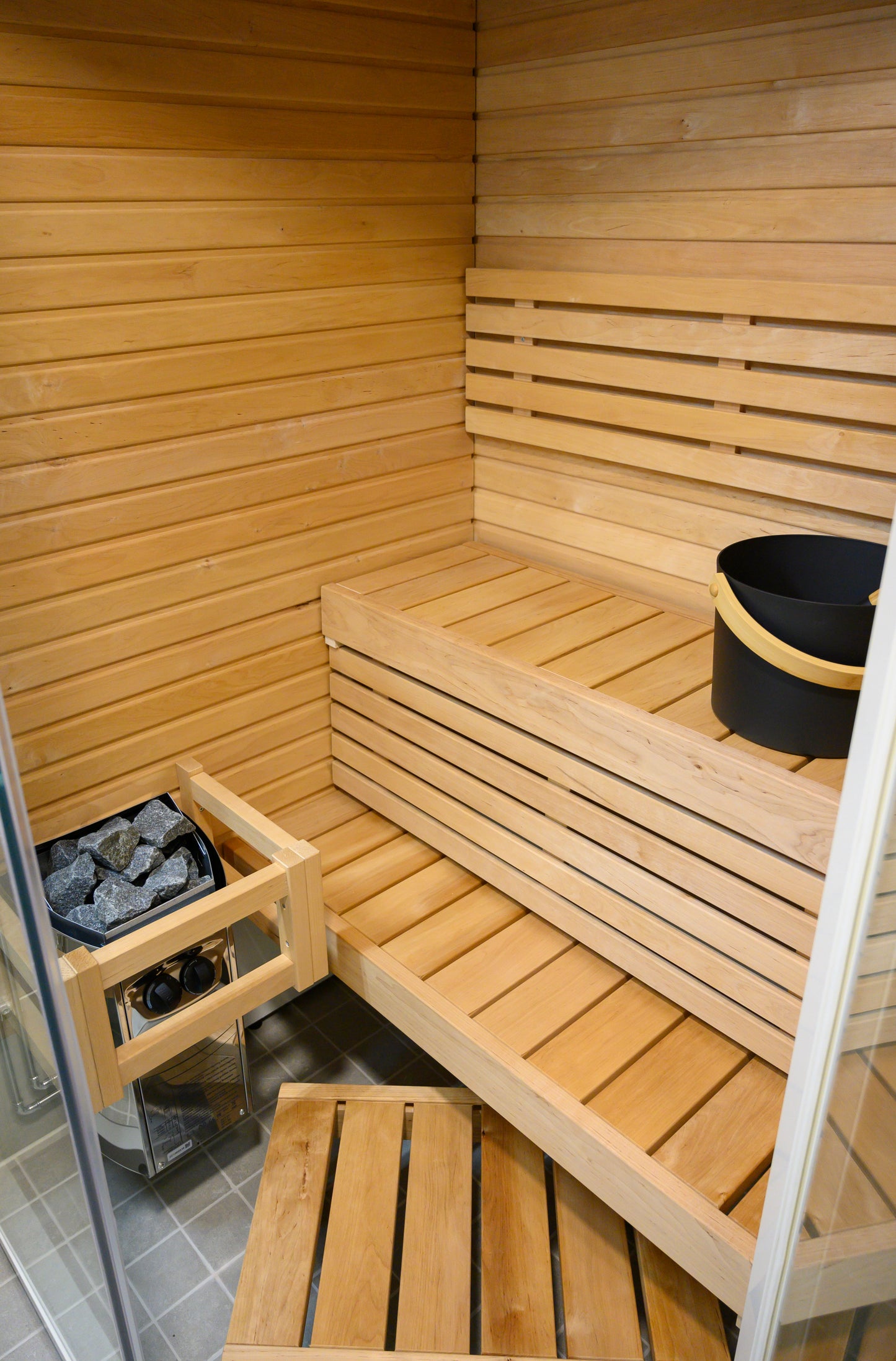 Sauna angolare Sirius con secchio e pietre.