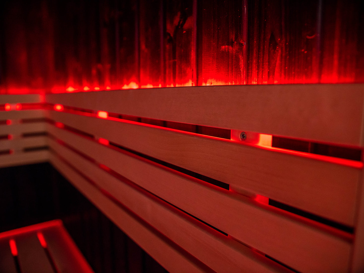 Sauna Fenix con luce LED rossa su panca di legno.