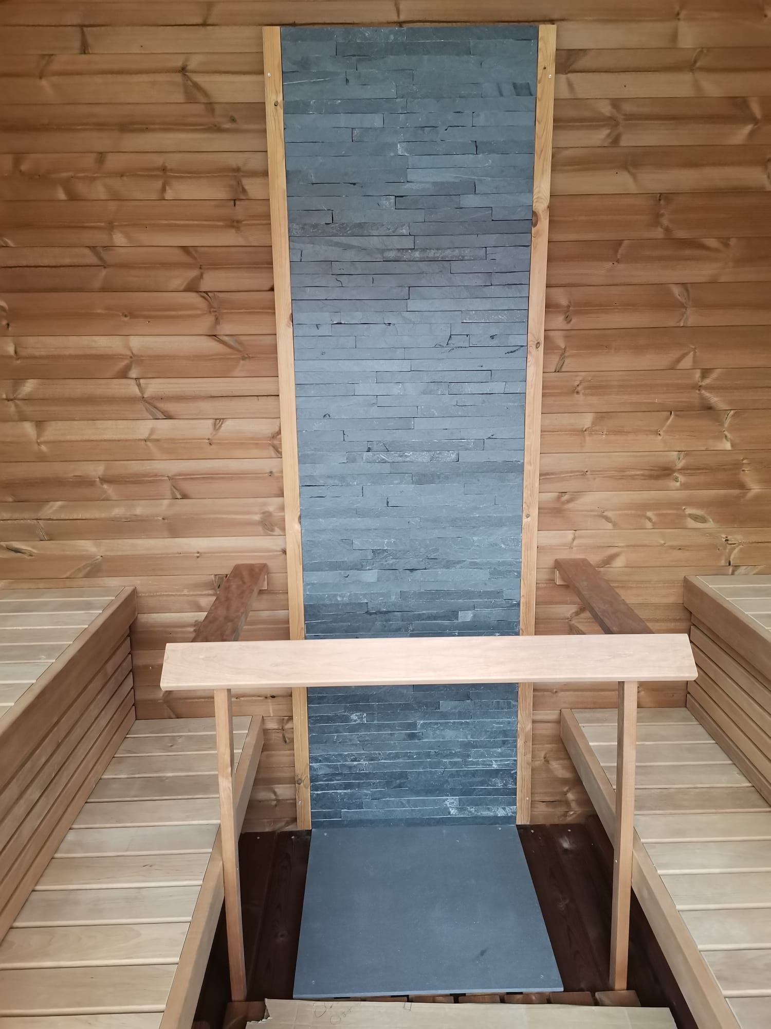 Saunamo Sauna Cubus con parete in pietra e panche in legno.