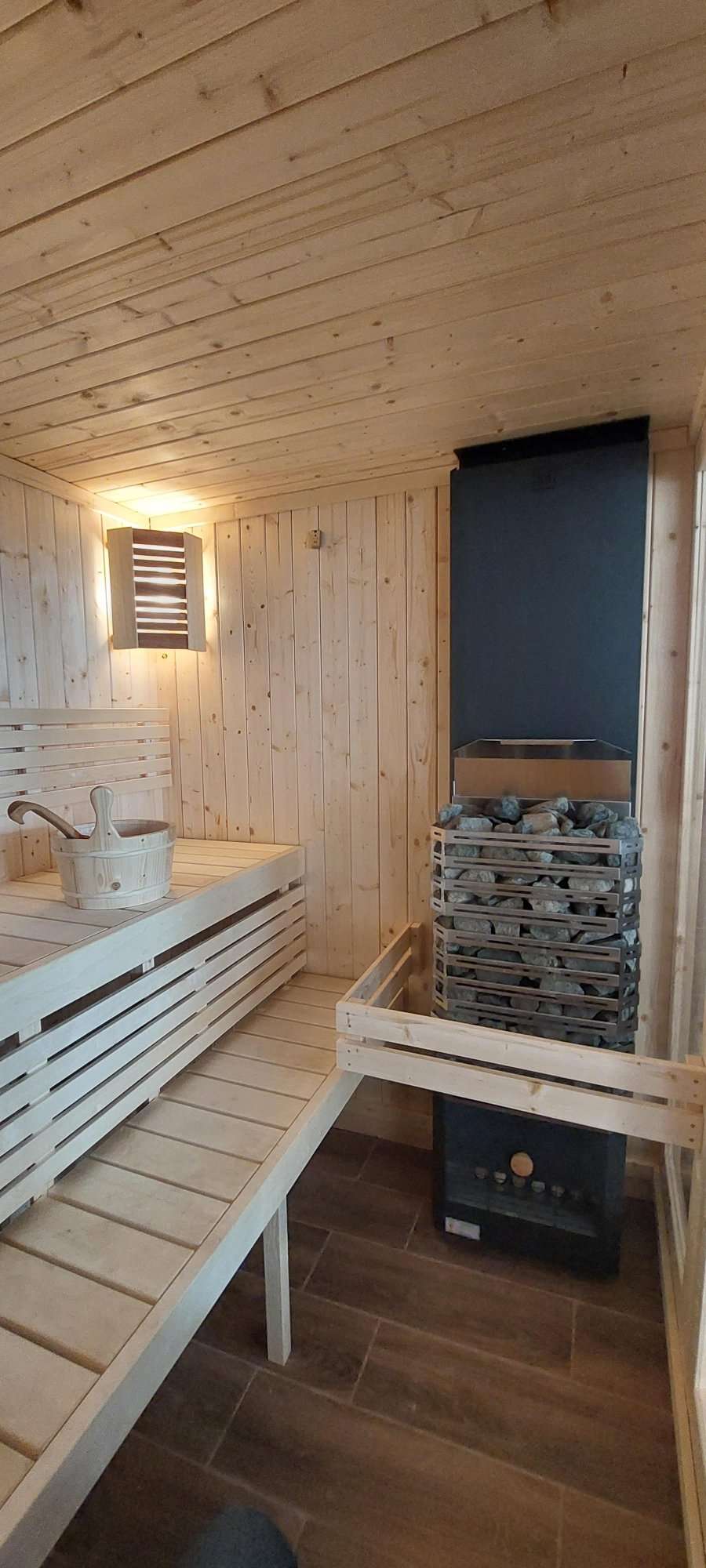 Grande sauna interna con secchio e pietre.